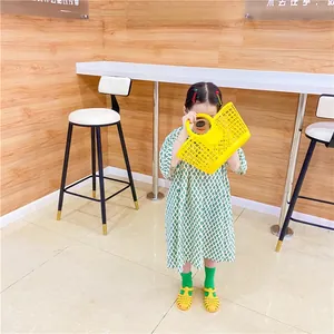Detail of yellow hollow plastic basket bag for girls styled with a green summer dress