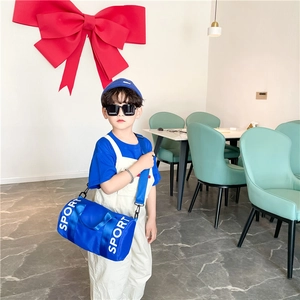 Detail of blue cylindrical kids sport crossbody bag with white SPORT text print
