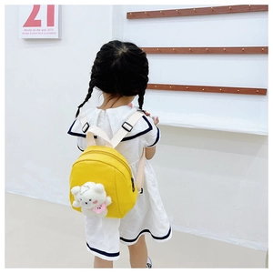Rear view of a girl wearing a cute yellow canvas toddler backpack with a white plush bear