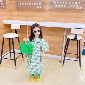 Close-up of a green hollow plastic basket with a summer girl dress and accessories
