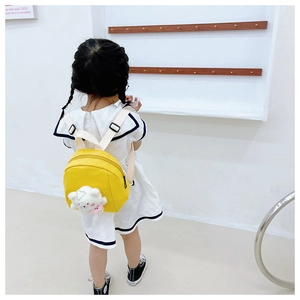Rear view of a yellow canvas child backpack featuring a 3D plush bear accessory