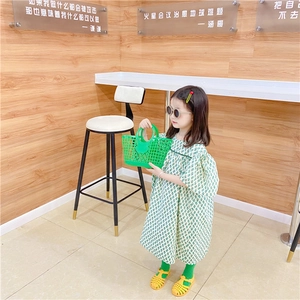 Detail of a bright green hollow woven plastic beach basket held by a young girl