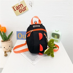 Détail du sac à dos dinosaure noir pour enfants avec bretelles orange et peluche décorative