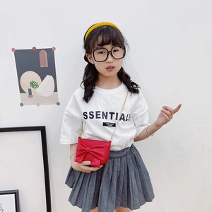Girl's red crossbody bag with oversized bow and gold metal chain strap on model
