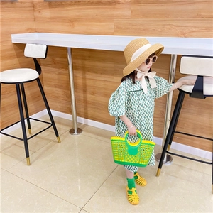 Kid's hollow woven beach basket bag in yellow and green paired with a summer outfit