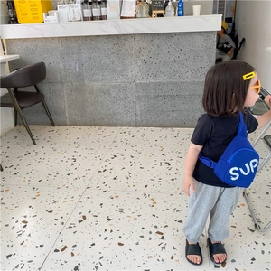 Detail of blue canvas kids crossbody bag with white SUP lettering and adjustable strap