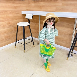 Detail of a girl wearing a green plaid puff sleeve dress with a coordinating beach basket