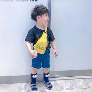 Sacoche croisée jaune pour enfant avec lettrage vert portée par un jeune mannequin