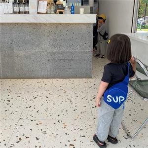 Detail of blue kids chest bag with white SUP lettering and durable nylon fabric strap