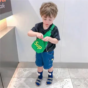 Sac bandoulière enfant en nylon vert fluo avec logo Sup porté par un jeune mannequin