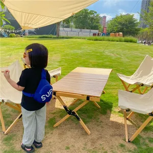 Blue kids crossbody bag with white SUP lettering shown in an outdoor park setting