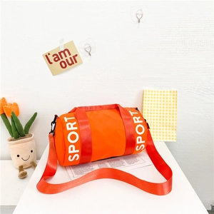 Detail of orange cylindrical sports bag with SPORT print and black hardware buckles