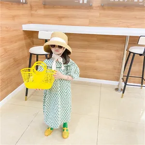 Detail of yellow hollow plastic basket paired with green check dress and woven straw hat