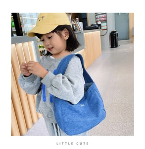 Close-up of blue denim kids crossbody bag with white embroidery on a small model