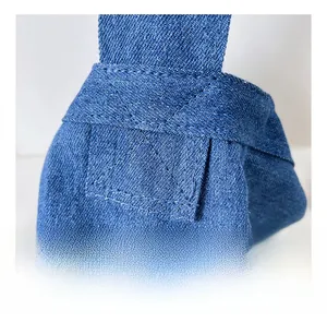 Macro detail of blue denim canvas shoulder bag showing reinforced cross-stitching texture