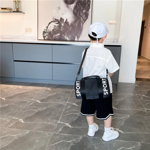 Black kids cylindrical sports crossbody bag with SPORT text shown on a child's back