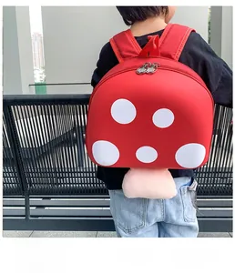Rear view of a child wearing the red mushroom shaped hard shell backpack outdoors