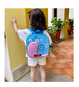 Close-up of cute snail-shaped hardshell kids backpack on a child in a bright outdoor setting