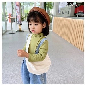 Toddler girl wearing canvas crossbody bag and denim overalls in a cafe setting