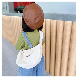 Detail showing embroidered letter on cream canvas kids crossbody bag with beret