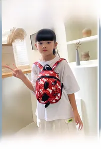 Detail view of a red toddler backpack with white dinosaur prints and black straps