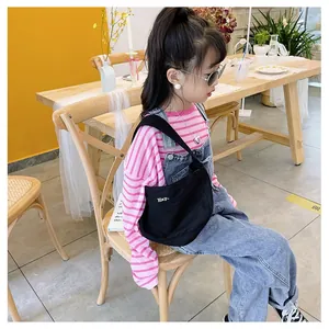 Detailed view of child's black canvas crossbody bag with white Hey- embroidery on model