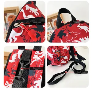 Detail of red dinosaur backpack with metal zipper, handle, and detachable safety leash