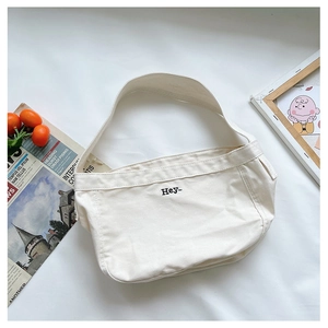 Detail of white canvas crossbody bag featuring black Hey- embroidery and fine stitching