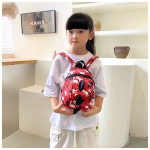 Detail view of red kids backpack with white dinosaur prints and 3D black dorsal fins