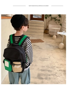 Kids fashion backpack with green contrast straps and utility pockets shown on a child