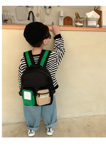 Close-up of kids backpack with green straps and contrast pockets in a cozy cafe setting