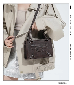 Detail view of dark coffee motorcycle bag with metallic studs and decorative zippers