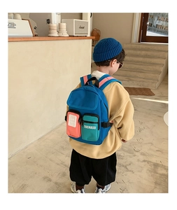 Detailed view of kids colorful backpack with multiple zipped pockets on child model