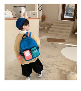 Detail showing color-blocked zipper pockets and embroidered text on children's backpack