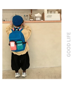 Rear view of a child wearing a colorful TOCHASO backpack in a cozy cafe setting
