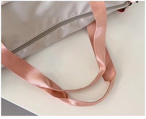 Close-up of cream travel bag showing pink reinforced handles and smooth zipper details