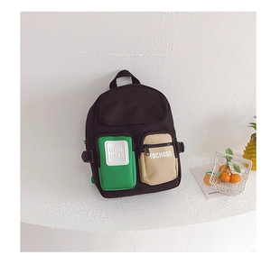 Detail view of stylish kids backpack with contrasting green and beige front pockets