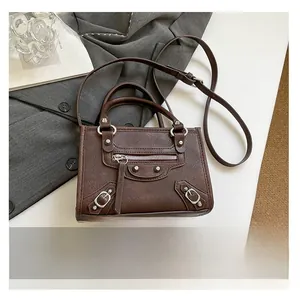 Mini retro motorcycle bag in dark brown leather with rivets compared to a phone size