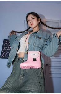 Pink rain boot shaped crossbody bag with black buckle detail and slender shoulder strap