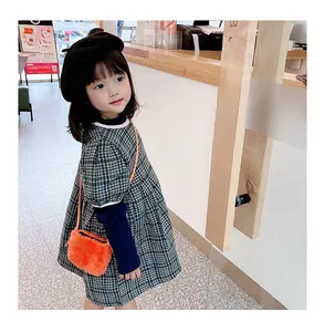 Nahaufnahme einer orangefarbenen Kinder-Plüschtasche mit Karokleid und schwarzer Baskenmütze