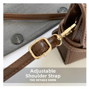 Detail of adjustable leather shoulder strap with gold buckle on a brown handbag