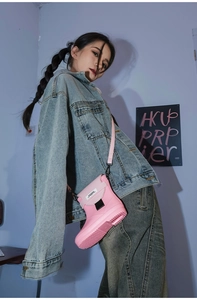 Detail of creative pink boot-shaped crossbody bag with adjustable strap on a denim outfit