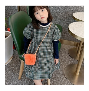 Detailaufnahme eines Mädchens im grünen Karo-Kleid mit einer orangen Plüsch-Umhängetasche