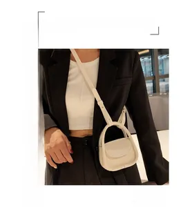Detail of a creamy white semi-circular handle handbag styled with a black blazer