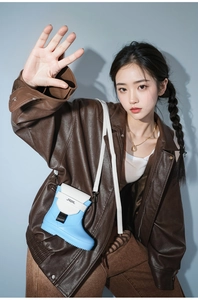 Detail view of a cute blue boot-shaped crossbody bag with adjustable white strap
