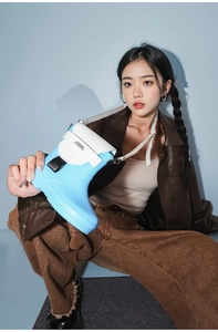 Detailed view of sky blue rain boot shaped bag with white pocket and logo strap