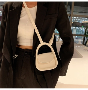 Close-up of a minimalist white mini crossbody bag featuring a round top handle design