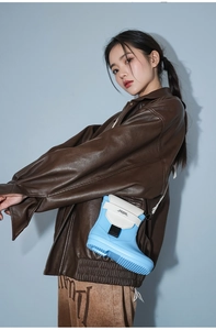 Close-up of sky blue boot-shaped crossbody bag featuring creamy leather flap and metal buckle