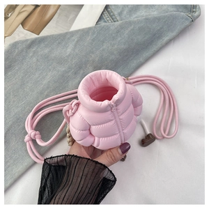Detailed close-up of pink quilted puffer bag showing glossy nylon fabric and woven strap