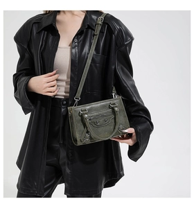Detail of olive green leather motorcycle bag with metal studs and tassel zippers